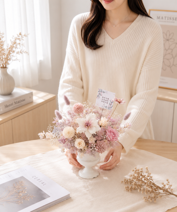 開幕送什麼花永生花桌花人物情境照，白色陶瓷高腳盆器搭配粉色不凋花，適合開店祝賀與質感開幕花禮。